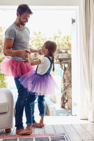 Daughter on father feet, ballet dancing and fun with learning at home in tutu, bond with love and creativity. Family, man and girl dance in living room, ballerina lesson and spending time togetherの写真素材