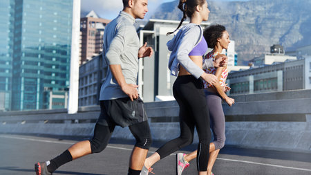 Putting the miles behind them. a group of friends jogging together through the city.の写真素材