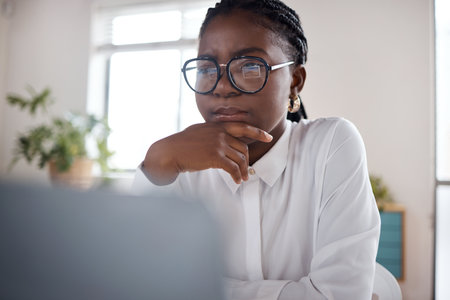 Emails can make or break your day. a young businesswoman using a laptop in a modern office.の写真素材