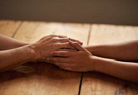 Support, unity and closeup of people holding hands for grief, hope and sympathy after loss. Gratitude, empathy and friends in an intimate moment with affection for love, trust and solidarity on tableの写真素材