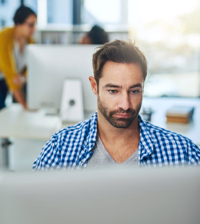 Following a career in graphic design. a businessman working on a computer in a modern office.