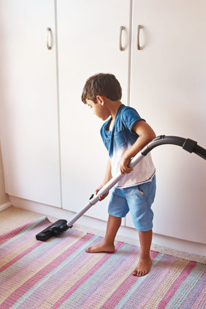 Vaccuming carpet, clean and a child in room for chores, learning and housework with a vacuum. Housework, house and a boy kid cleaning a mat for responsibility, routine and with machine in a bedroomの写真素材