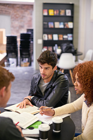 Students studying in a group in library on campus, people learning for university education and...