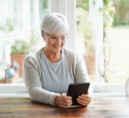 Tablet, senior woman and online in house with social media, reading news app and relax with ebook....
