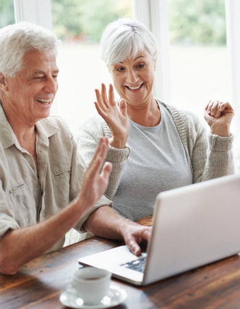Happy elderly couple, laptop and waving on video call, internet communication and voip chat at home. Senior man, old woman and wave hello on computer for virtual conversation, contact and connectionの写真素材