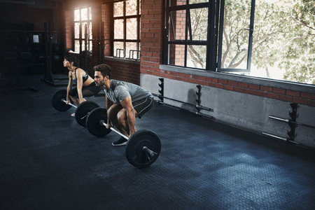 Youre only as strong as you think you are. a young man and woman working out with weights at the...