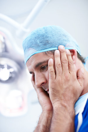 I did all I could. A helpless looking doctor holding his head in his hands.の写真素材
