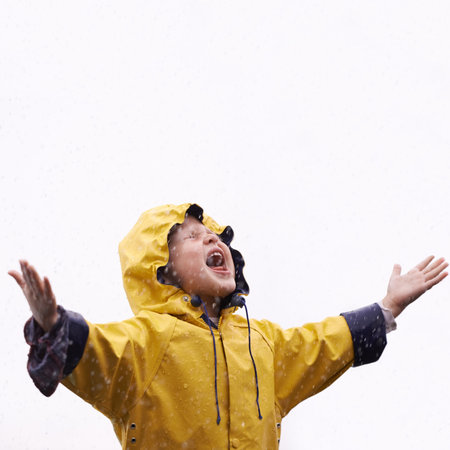 Girl child, rain and playing with space for mockup with shouting, happiness or winter fashion. Female kid, raincoat or playful with water, open hands or screaming on adventure with freedom in mock upの写真素材