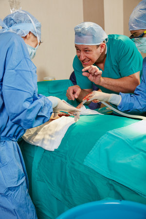 Clamp down with a tiny bit of pressure. a surgeon giving his colleague advice during a surgical procedure.の写真素材