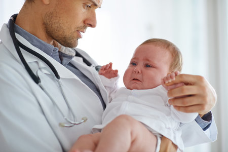 Doctor, pediatrician and crying baby in clinic for medical assessment, support and growth. Sad, scared and sick newborn kid with pediatrics physician for healthcare service, hospital test or wellnessの写真素材