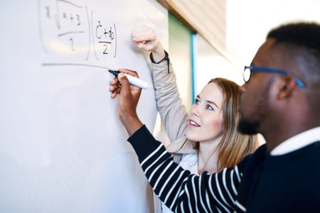 Sharing an important technique. a young man writing on a whiteboard while students look on.