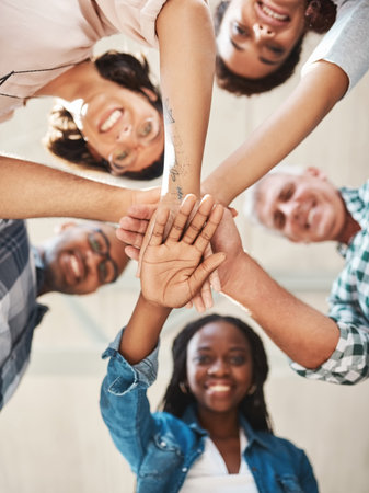 Put business growth in the hands of the team. Low angle shot of a group of creatives stacking their...