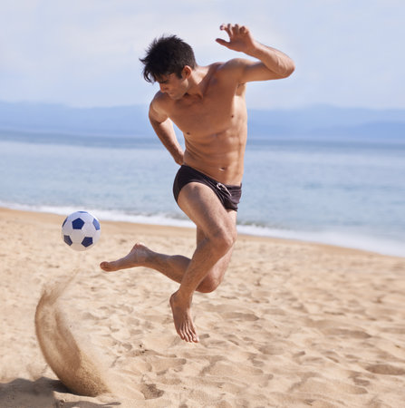 My kind of beach ball. A handsome young man playing soccer on the beach.の写真素材