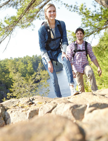 Taking a moment to rest. A young couple hiking and climbing up the mountainside together.