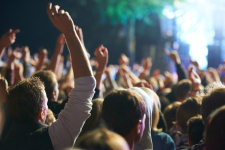 Hands raised to their favourite artist. Rear view shot of a crowd enjoying a live musical...