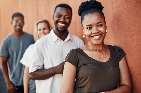 Nothing but smiles. Cropped portrait of an attractive young businesswoman standing with her colleagues against a wall outside.の写真素材