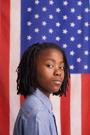 Young patriot. Portrait of a confident young boy standing in front of an American flagPortrait of a confident young boy standing in front of an American flag.の写真素材