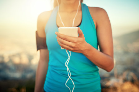 Theres a playlist for that. a young woman listening to music while out for a run.の写真素材
