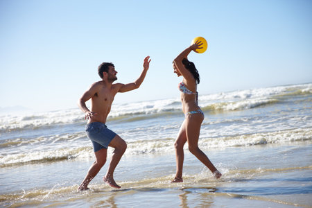 Theyre well matched. a happy couple playing in the shallow water together on the beach.の写真素材