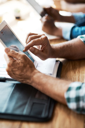 Who needs notebooks in the boardroom these days. a businessman using a digital tablet during a...