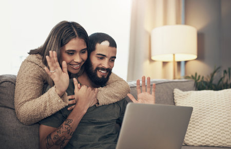 The best way to survive social distance. a young couple using a laptop to make a video call on the sofa at home.の写真素材