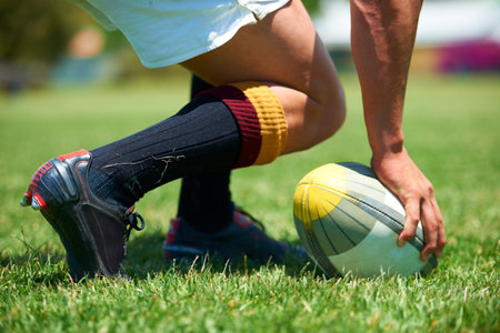 Hand, rugby and ball with a sports man playing a game on a grass field for competition or recreation. Fitness, training and health with a male athlete getting ready to play a match outdoor in summerの写真素材