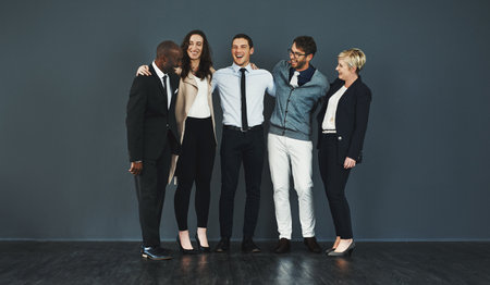 Theyre in high spirits. Studio shot of a group of businesspeople standing against a grey background.の写真素材