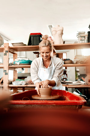Focus on what you love and make money at it. a female artisan working in her pottery workshop.の写真素材