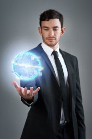 Defy business limits and go global. Studio shot of a young businessman holding a glowing orb against a gray background.の写真素材
