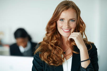 Success is guaranteed if you keep your ambitions in sight. Portrait of a young businesswoman standing in an office with colleagues in the background.の写真素材