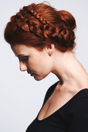 Beautifully braided. Studio shot of a beautiful redhead woman with a braided up-do posing against a...