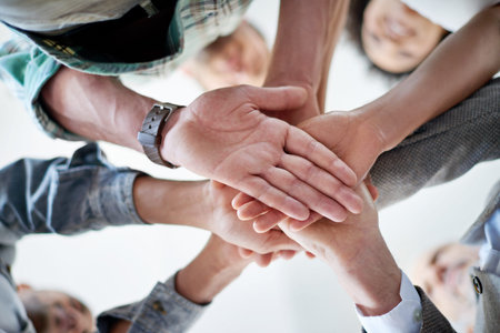 Theyre in it together. Low angle shot of a group of coworkers standing in a huddle in an office.