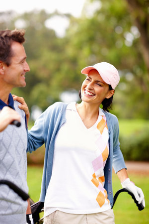 Smiling couple on golf course. Smiling couple standing on golf course and looking at each other.の写真素材