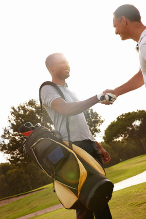 I agree to beat you fair and square. two young men shaking hands on a golf course.の写真素材