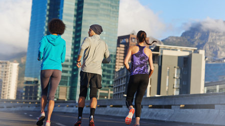 Putting the miles behind us. Rearview shot of three young joggers out for a run in the city streets.の写真素材