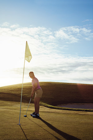 The proof is in the putting. a woman playing golf on a sunny day.の写真素材