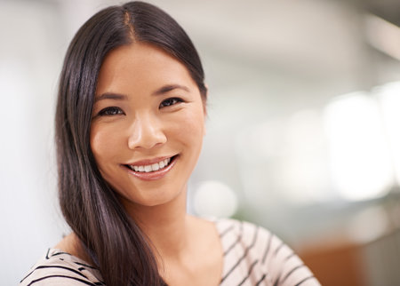 Shes optimistic about her future with the company. An attractive young asian businesswoman looking at the camera.の写真素材