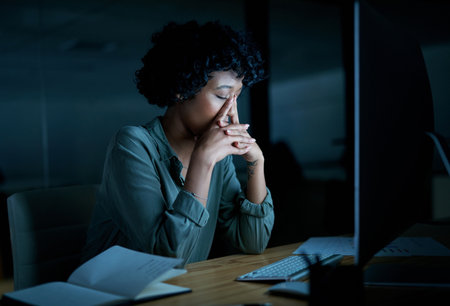 Its never too late to start again. a young businesswoman looking stressed while using a computer during a late night at work.の写真素材
