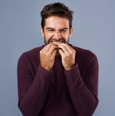 My nerves are shot. Studio shot of a handsome young man looking scared against a gray background.
