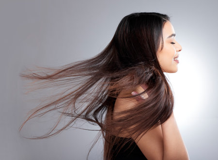 Long, luscious and shiny strands. Studio shot of an attractive young woman posing against a grey background.の写真素材