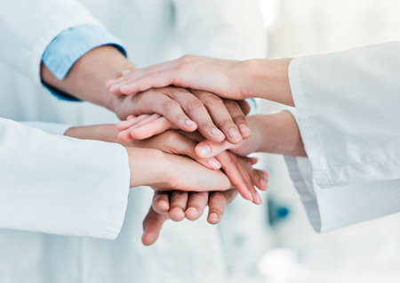 Improving the world through science in leaps and bounds. Closeup shot of a group of unrecognisable scientists joining their hands together in a huddle in a lab.の写真素材