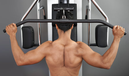 Striving for full body fitness. Rear view of a young ethnic man working out at the gym.