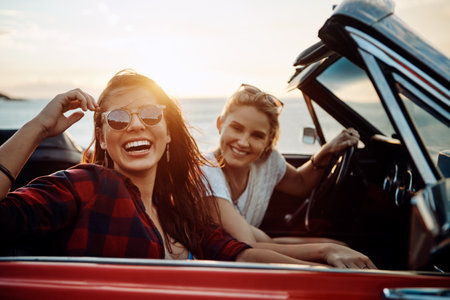 The road doesnt feel long when youre having fun. a two happy young women enjoying a summers road trip together.の写真素材