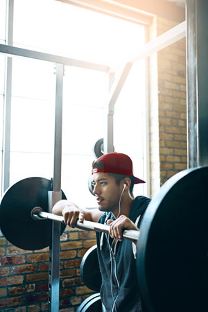 Dont hold back. a man doing weight training at the gym.の写真素材