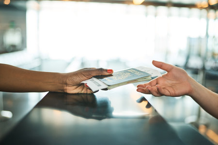 Hands, passport and airport service counter closeup or boarding flight, support and travel desk consultant. Travelling agent, checkin and person help traveller with id book, ticket and safe journeyの写真素材