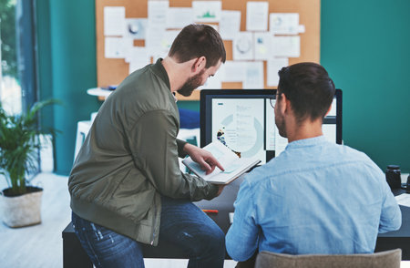 Theres a creative solution to every problem. Rearview shot of two young designers working together in an office.の写真素材