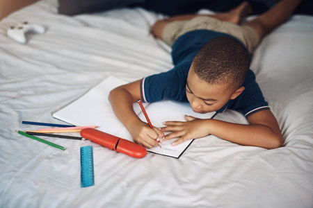 He always does his homework without being told. a young boy using a pencil while writing at home.
