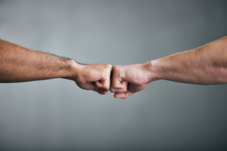 Go out and get it. two unrecognizable male athletes fist bumping against a grey background.の写真素材