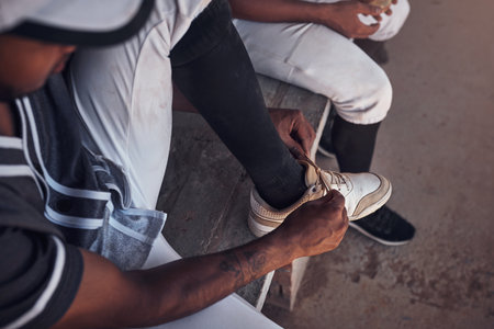 You better be ready for what hes about to bring. a young man tying his shoelaces before playing a game of baseball.の写真素材