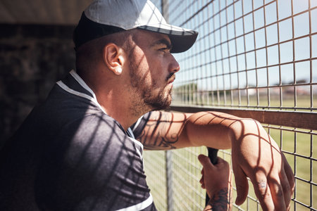 When we watch, we learn. a young man watching a game of baseball from behind the fence.の写真素材